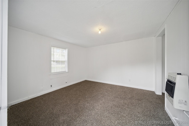 empty room with dark carpet and heating unit