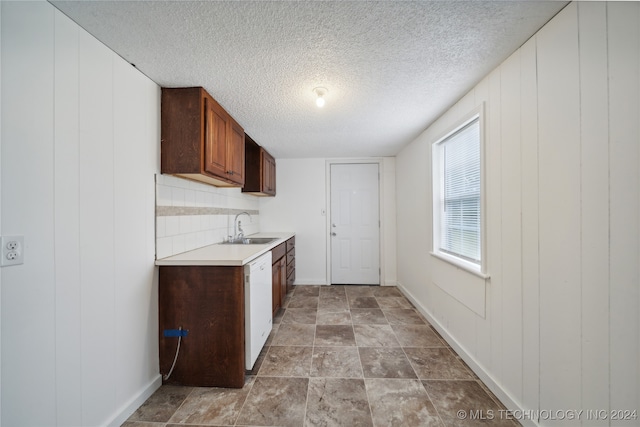 kitchen featuring white dishwasher, a textured ceiling, sink, and tasteful backsplash