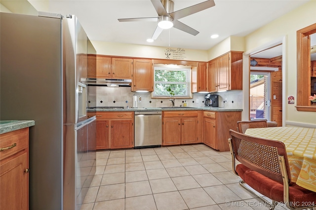 kitchen featuring backsplash, light tile patterned floors, stainless steel appliances, ceiling fan, and sink