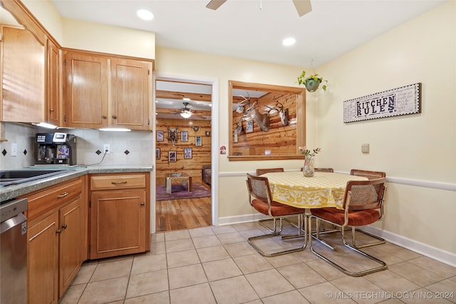 kitchen featuring dishwasher, light tile patterned flooring, decorative backsplash, wooden walls, and ceiling fan