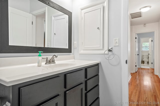 bathroom with hardwood / wood-style floors, vanity, and toilet