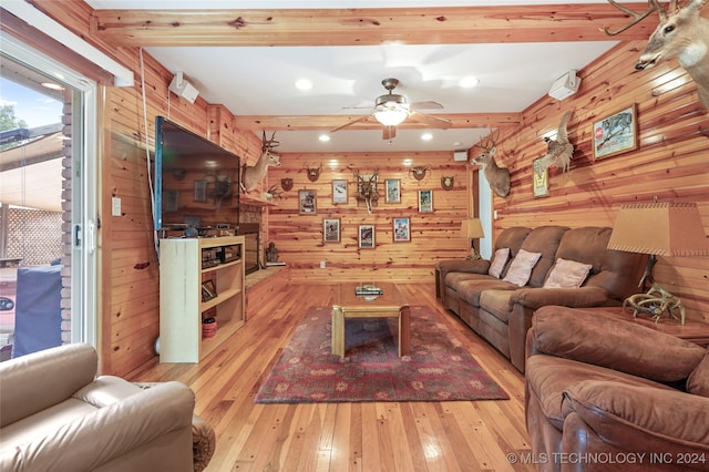 living room with ceiling fan, beamed ceiling, light hardwood / wood-style flooring, and wood walls