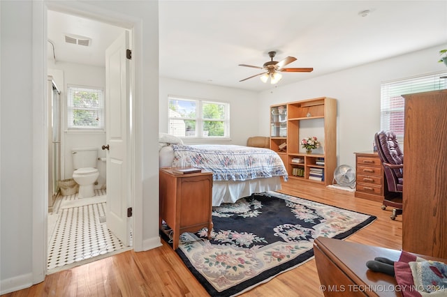 bedroom with light hardwood / wood-style floors, ensuite bathroom, and ceiling fan