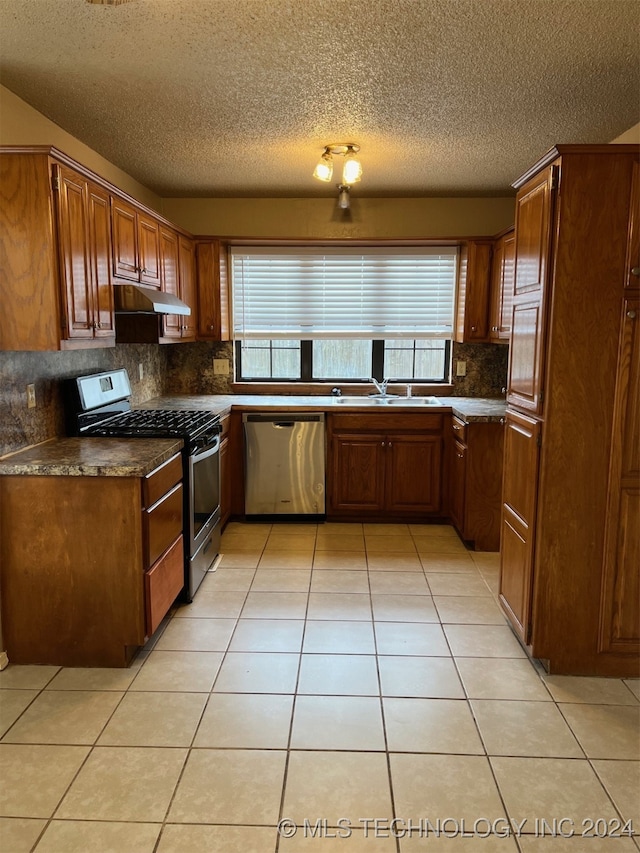 kitchen featuring light tile patterned floors, appliances with stainless steel finishes, a healthy amount of sunlight, and a textured ceiling