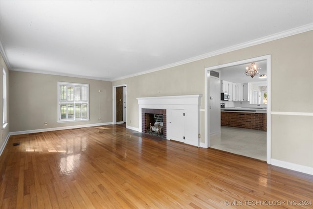 unfurnished living room with light hardwood / wood-style floors, a fireplace, ornamental molding, and a chandelier