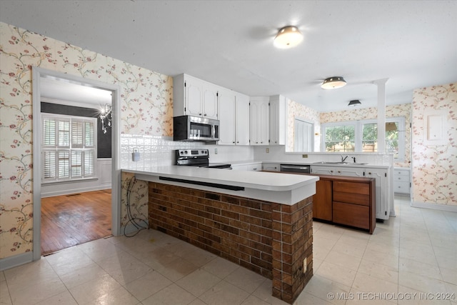 kitchen with sink, kitchen peninsula, light hardwood / wood-style flooring, white cabinetry, and appliances with stainless steel finishes