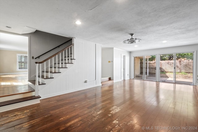 unfurnished living room featuring ceiling fan, a textured ceiling, hardwood / wood-style floors, and a wealth of natural light