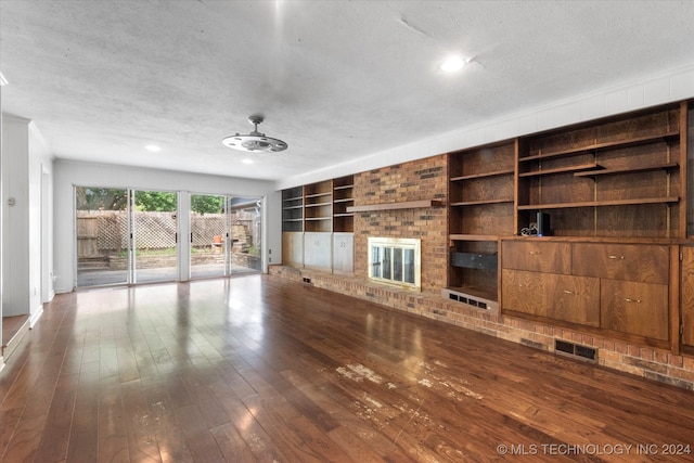 unfurnished living room with a brick fireplace, a textured ceiling, wood-type flooring, and ceiling fan