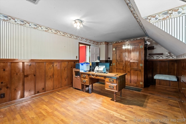 office featuring light hardwood / wood-style flooring, wooden walls, and vaulted ceiling