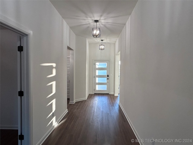 doorway to outside with dark wood-type flooring and an inviting chandelier