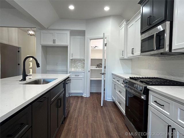 kitchen featuring stainless steel appliances, white cabinetry, sink, backsplash, and dark wood-type flooring