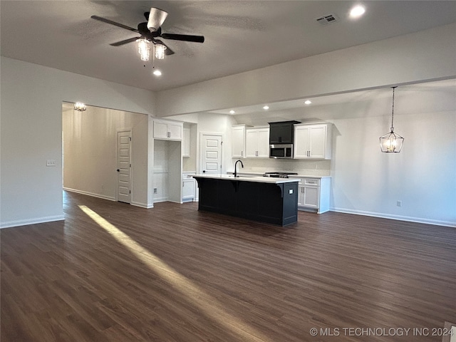 kitchen featuring dark wood-type flooring, a center island with sink, pendant lighting, and appliances with stainless steel finishes