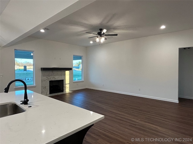 kitchen with dark hardwood / wood-style flooring, sink, a tile fireplace, and ceiling fan