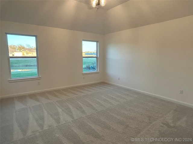 carpeted empty room featuring a water view, lofted ceiling, and ceiling fan