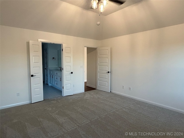 unfurnished bedroom featuring connected bathroom, lofted ceiling, ceiling fan, and dark carpet