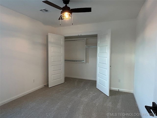 unfurnished bedroom with ceiling fan, dark carpet, and a closet