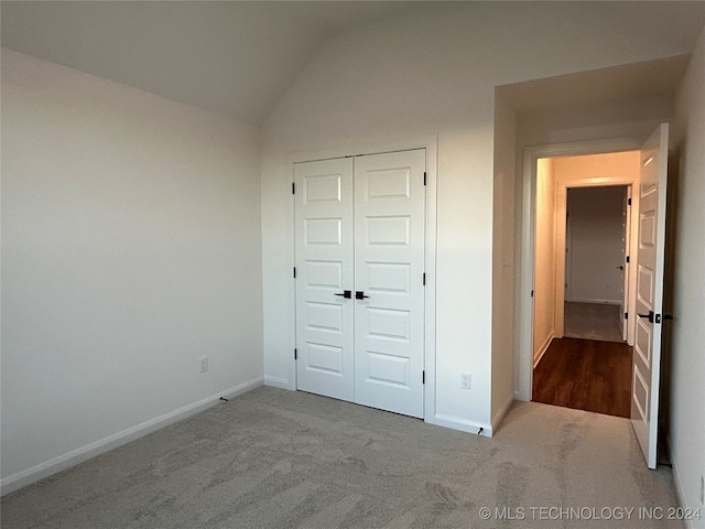 unfurnished bedroom featuring lofted ceiling, a closet, and carpet floors