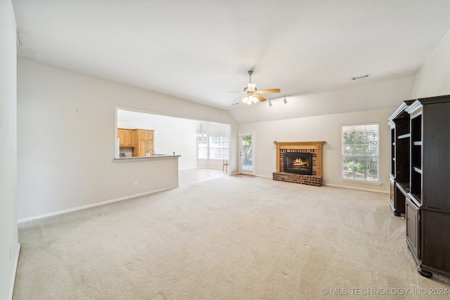 unfurnished living room featuring ceiling fan, light colored carpet, vaulted ceiling, and a brick fireplace