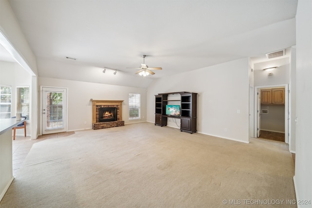 unfurnished living room with track lighting, a brick fireplace, light colored carpet, ceiling fan, and lofted ceiling