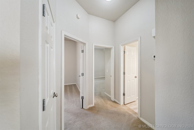 hallway with light carpet and a towering ceiling