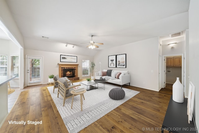 living room with a brick fireplace, ceiling fan, and dark wood-type flooring