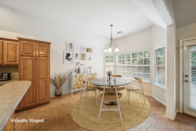 dining area with light tile patterned floors, lofted ceiling, and an inviting chandelier