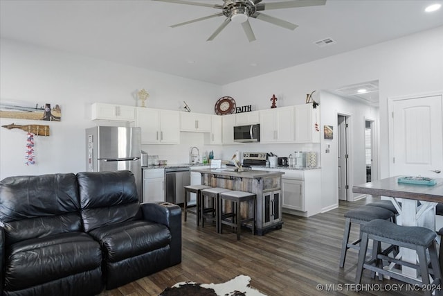 living room with dark hardwood / wood-style flooring, ceiling fan, and sink