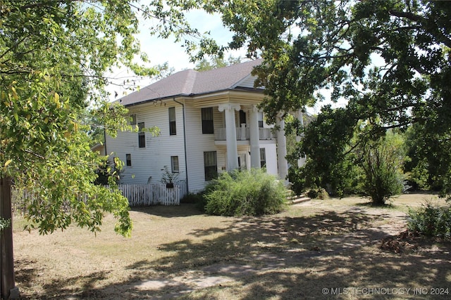 512 N 4th St, Henryetta, OK 74437 - view of side of property featuring a shingled roof, fence, and a balcony