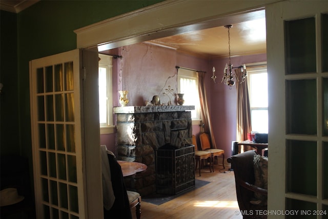 living area with a fireplace, a notable chandelier, light hardwood / wood-style floors, and ornamental molding