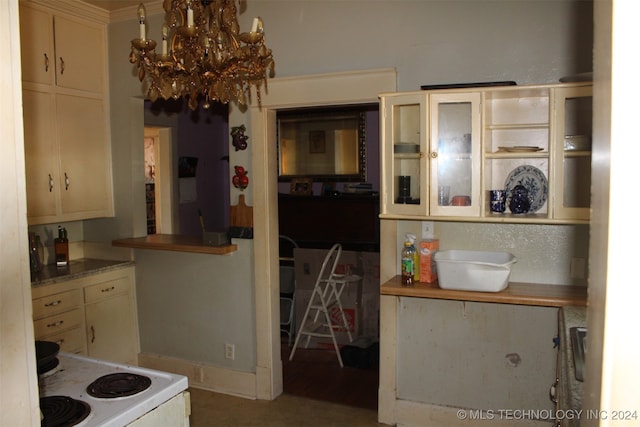 kitchen featuring ornamental molding, cream cabinets, white stove, and a chandelier