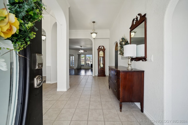 foyer featuring ceiling fan, crown molding, and light tile patterned floors