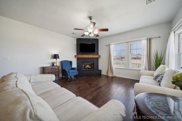 living room featuring dark hardwood / wood-style flooring, ceiling fan, and a brick fireplace