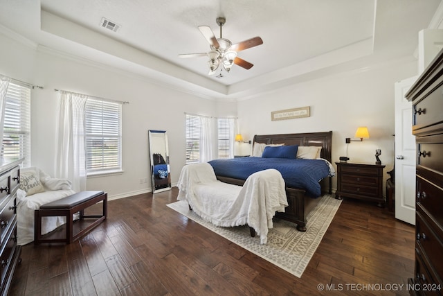 bedroom with ceiling fan, a raised ceiling, and dark hardwood / wood-style flooring