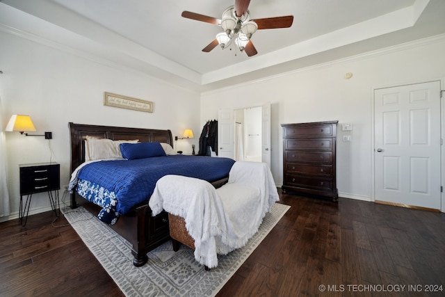 bedroom with ceiling fan, a tray ceiling, and dark hardwood / wood-style flooring