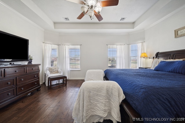 bedroom with ceiling fan, a tray ceiling, crown molding, and dark hardwood / wood-style flooring