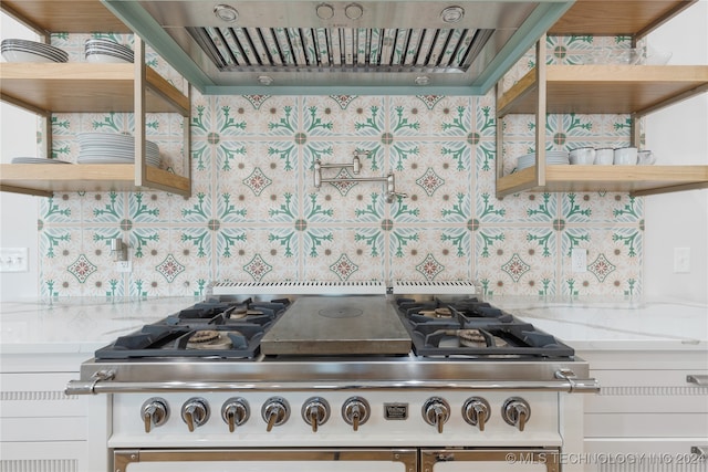 interior space with light stone counters, exhaust hood, and white cabinetry