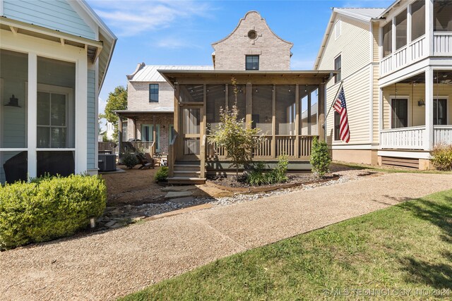 view of front of home featuring a front lawn, a sunroom, and central air condition unit