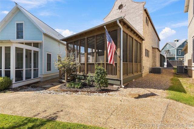 rear view of property with a sunroom and cooling unit