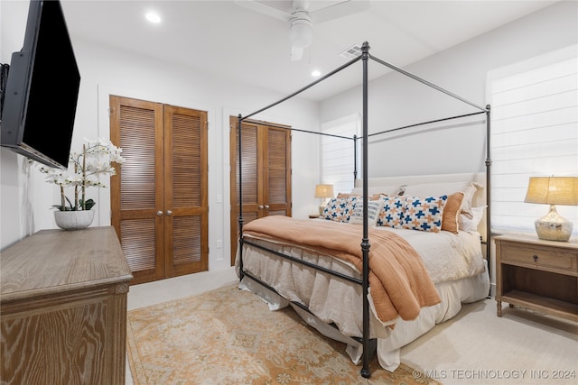 carpeted bedroom featuring multiple closets and ceiling fan