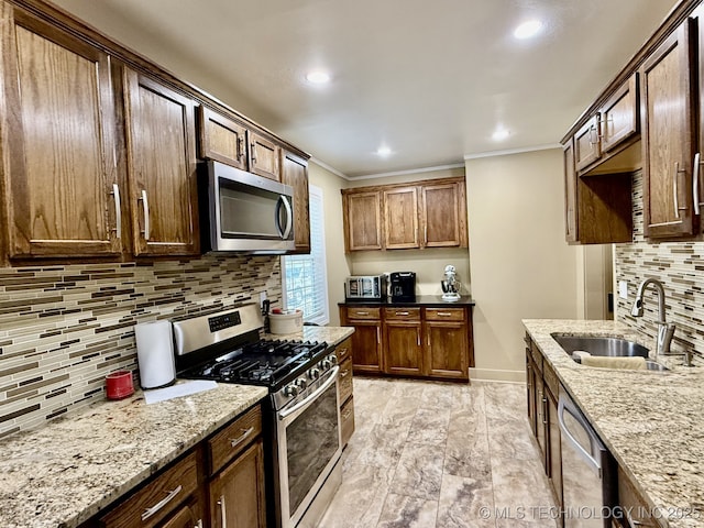 kitchen featuring light stone counters, sink, crown molding, and stainless steel appliances