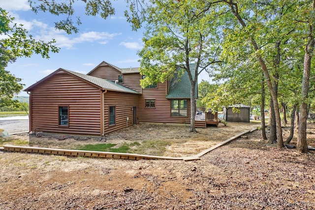 rear view of house featuring a wooden deck and a shed