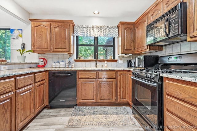 kitchen with black appliances, plenty of natural light, light hardwood / wood-style floors, and decorative backsplash