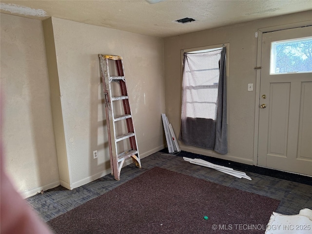 foyer with baseboards and a textured ceiling