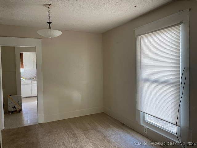 carpeted empty room featuring a textured ceiling