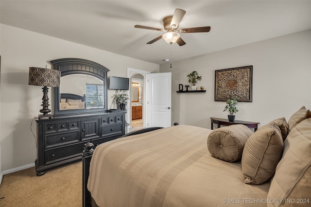 bedroom featuring ceiling fan, light colored carpet, and ensuite bathroom