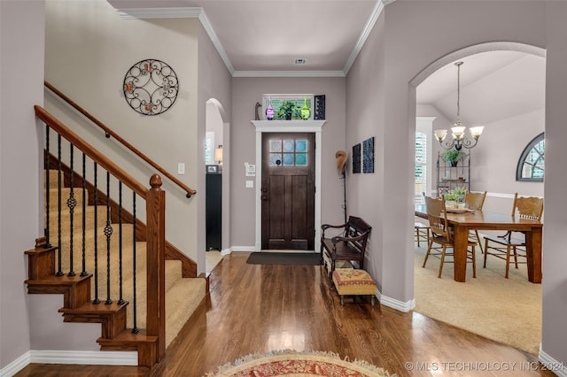 foyer featuring wood-type flooring, an inviting chandelier, and ornamental molding