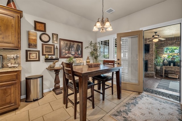 dining room with a fireplace, light tile patterned floors, ceiling fan with notable chandelier, and plenty of natural light