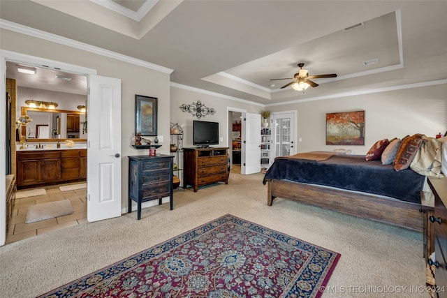 carpeted bedroom featuring a tray ceiling, connected bathroom, ceiling fan, and crown molding