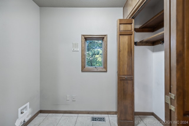 laundry room featuring washer hookup, light tile patterned floors, and a textured ceiling