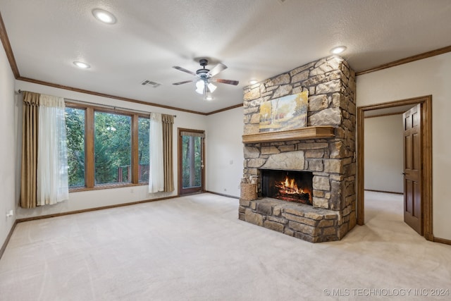 unfurnished living room with carpet floors, ceiling fan, a fireplace, ornamental molding, and a textured ceiling